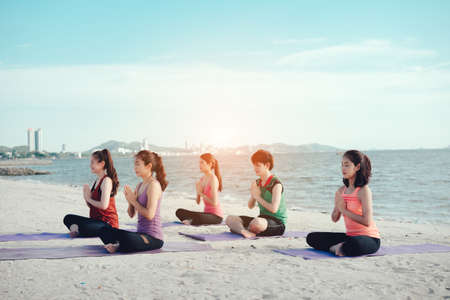 Young group yoga exercise practice  with pose on the beach relax vacation in summerの写真素材