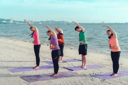Young group yoga exercise practice  with pose on the beach relax vacation in summerの写真素材