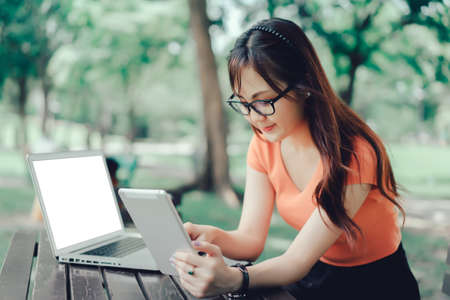Young girl using tablet and laptop computer marketing online concept at at park outdoorの写真素材