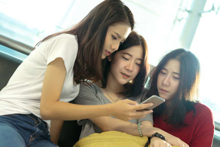 Young girl asian group traveler using smartphone and backpack with carrying hold suitcase luggage and passenger for tour travel booking ticket flight in airport international vacation relaxation.の写真素材