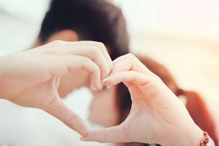 Young man and girl Couple in love gesturing heart with fingers against  romantic  leisure in...