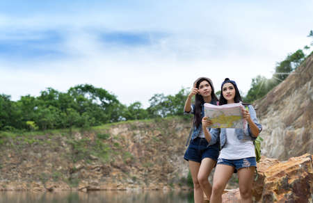 Young girl asian together with backpack standing on big rock open maps location travel trip...