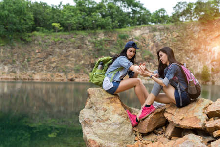 Young girl asian with backpack help friend hurt arm first aid elementary on the mountain travel trip adventureの写真素材