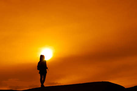 Young girl asian with backpack travel trip stand finish destinations on the mountain looking view sunset silhouetteの写真素材