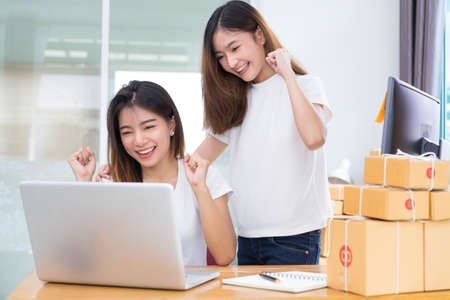 Young asian girl together teamwork freelancer small business private working at home office with laptop, note, phone, packaging delivery online market on purchase checking orders to customer.の写真素材