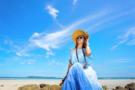Young asian girl in hawaii dress with hat, sunglasses, camera on sea beach summer fun and happy relax in vacation timeの写真素材