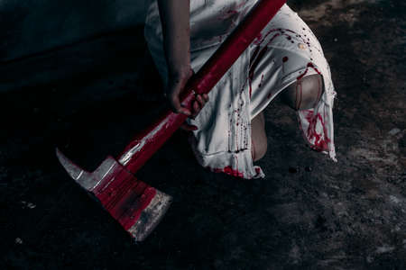 Zombie woman or ghost holding axe sitting with blood in house of ruin nightmare, horror of scary...