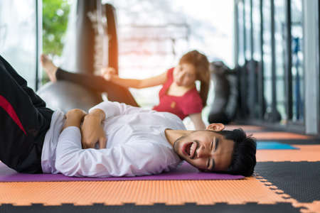 Young asian man and woman injured exercise erobics with yoga ball indoor for building muscle, slim body and strong perfectの写真素材