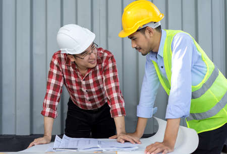 Engineer men with safety helmet working teamwork building consult project in side construction in industy with paper plan on tableの写真素材
