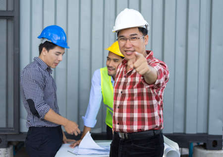 Three Engineer men with safety helmet working teamwork building consult project in side construction in industy with paper plan on tableの写真素材