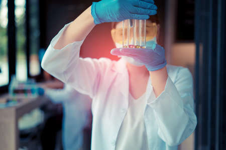 Scientist woman with glasses working reserch and conducts experiments by synthesising compounds in laboratory and the test tubeの写真素材