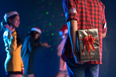 Young handsome man asian hidden gift box for giving girlfriend in christmas party celebrating new year midnight at clubの写真素材