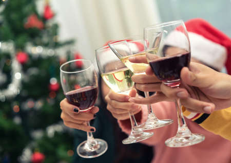 Closeup hands holding glass of wine, cocktail, champagne friend drinking celebration christmas home party interiorの写真素材
