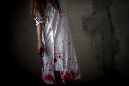 Closeup Ghost woman holding knife for kill with blood violence in house of ruin, nightmare, horror of scary fear on hell is monster devil in halloween festival, copy space the right.の写真素材