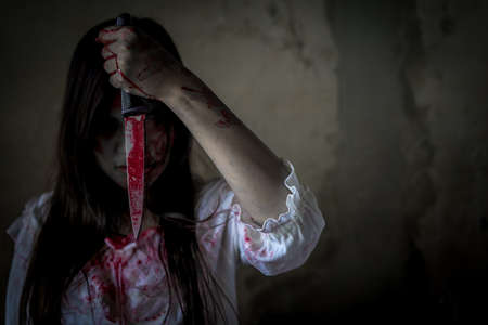 Ghost woman or zombie hold knife for kill with blood violence in house of ruin, nightmare, horror of scary fear on hell is monster devil in halloween festival, copy space the right.の写真素材