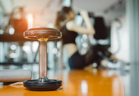 Young asian woman drinking protein shake from bottle after workout exercise for muscle at fitness gym healthy lifestyle bodybuilding sitting, Closeup dumbbellの写真素材