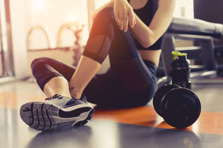 Woman exercise workout in gym fitness breaking relax holding protein shake bottle after training sport with dumbbell and healthy lifestyle bodybuilding.の写真素材