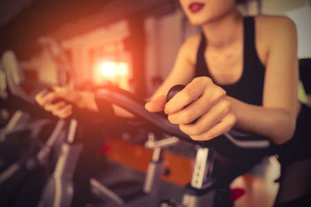 Exercise bike cardio workout at fitness gym of woman taking weight loss with machine aerobic for slim and firm healthy in the morning.