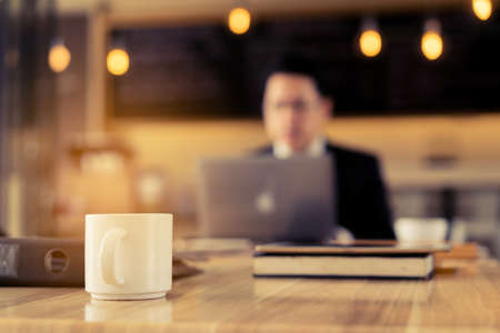 Businessman working at office table with laptop coworker and paper plan marketing project success, Closeup coffee cupの写真素材