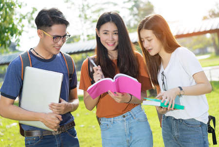 Students university asian together reading book study smiling with tablet,laptop computer at university high school campus,college in summer holiday relaxationの写真素材