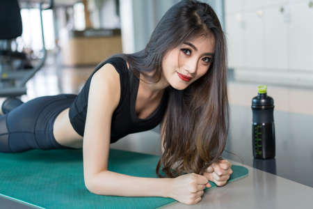 Exercise woman doing plank at gym workout fitness, athlete muscle building strong healthy lifestyle with protein shake bottleの写真素材