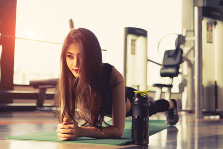 Exercise woman doing plank at gym workout fitness, athlete muscle building strong healthy lifestyle with protein shake bottleの写真素材