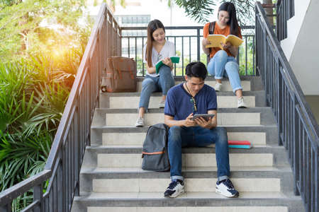 Students university asian together reading book study smiling with tablet at high school campus,college in summer holiday relaxationの写真素材