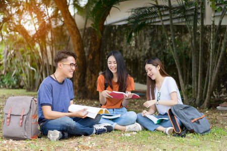 Students young asian together reading book study smiling with tablet,laptop computer at university high school campus,college in summer holiday relaxationの写真素材