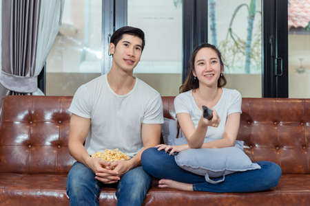Couple together watching television funny reaction on sofa in living room at room の写真素材
