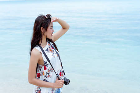 Asian woman taking photo with camera mirrorless at beach,Lifestyle hipster and travel relaxation,rest in summer season vacation concept の写真素材