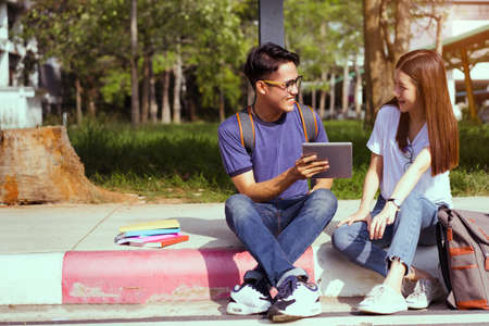 Students young asian together using laptop computer consult and reading book study smiling at university high school campus,college in summer holiday relaxationの写真素材