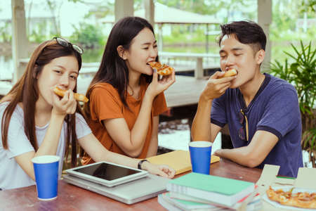 Asian group together eating pizza in breaking time having fun and enjoy party italian food slice with cheese delicious の写真素材
