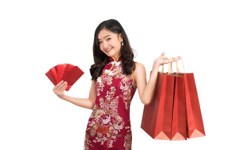 Asian woman wearing chinese dress hold Red envelopes and shopping bag cheongsam,qipao smile in chinese new year on white isolated backgroundの写真素材