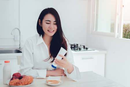 Asian woman making bread with sweetened condensed milk ,sweet spiced milk in the morning and eating apple fruit healthy food breakfast meal in kitchen room fresh start the day at home の写真素材