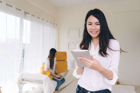 Freelancer asian women teamwork sme business working at office in home interior packing order for customer and online delivery for ready packing on living roomの写真素材