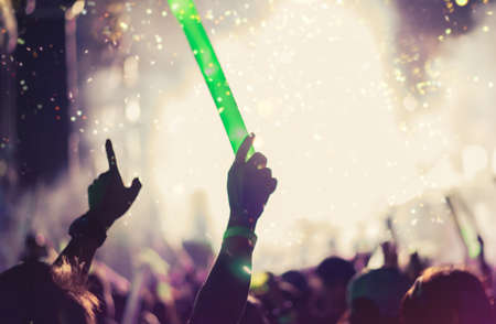 Crowd of hands up concert stage lights and people fan audience silhouette raising hands in the music festival rear view with spotlight glowing effectの写真素材