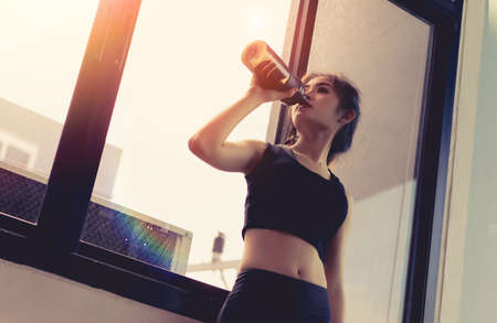 Asian woman exercise workout in gym fitness breaking relax drinking protein shake bottle after training sport healthy lifestyle bodybuilding.の写真素材