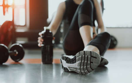 Woman exercise workout in gym fitness breaking relax holding protein shake bottle after training...