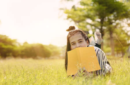Young woman student reading book in university campus college and study learning knowledge at park outdoorの写真素材