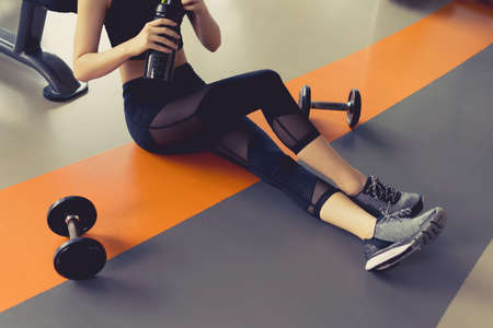 Woman exercise workout in gym fitness breaking relax after training sport with dumbbell and protein shake bottle healthy lifestyle bodybuildingの写真素材