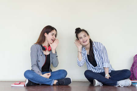 Teenagers women gossip girlfriend sharing secrets smiling sitting talking surprise in the ear, copy space backgroundの写真素材