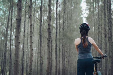 Woman riding bicycle in the forest her active activity fitness outdoor on autumn and summer healthy lifestyle workout adventure travel trip.の写真素材