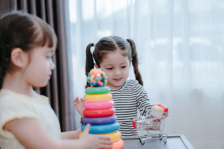 Children girls play a toy games in the room, Kids playing together with circular loop tower preschool and kindergarten education at home.の写真素材