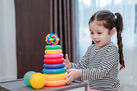 Children girl play a toy games in the room, Kid playing with circular loop tower preschool and kindergarten education at home.の写真素材