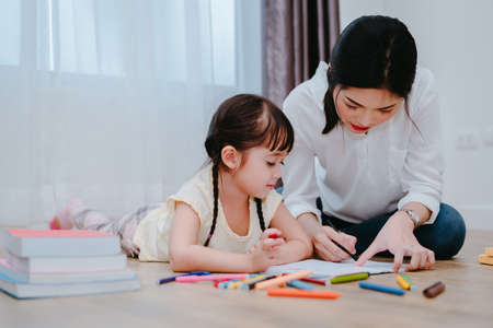 Mother and daughter study drawing with crayon paint on the paper family lifestyle, preschool and kindergarten education at home.の写真素材