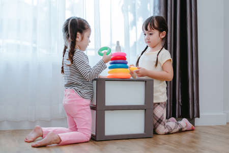 Children girls play a toy games in the room, Kids playing together with circular loop tower preschool and kindergarten education at home.の写真素材