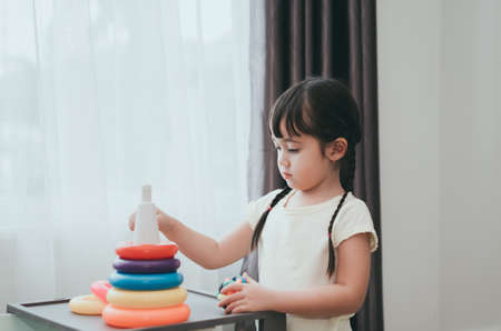 Children girl play a toy games in the room, Kid playing with circular loop tower preschool and kindergarten education at home.の写真素材