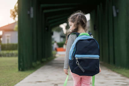 Kid girl pupil walking back to home after learning study school alone with schoolbag,preschool and kindergarten education concept.の写真素材