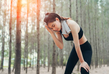 Asian woman exhausted or tired after training workout at spruce forest nature in the morning with cardio runner marathon,run out of energy healthy lifestyle.の写真素材