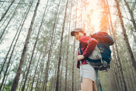 Asian woman traveler with backpack at spruce forest find the route go to destinations, girl traveler doing vacation relax enjoying and hiking to mountain travel lifestyle.の写真素材